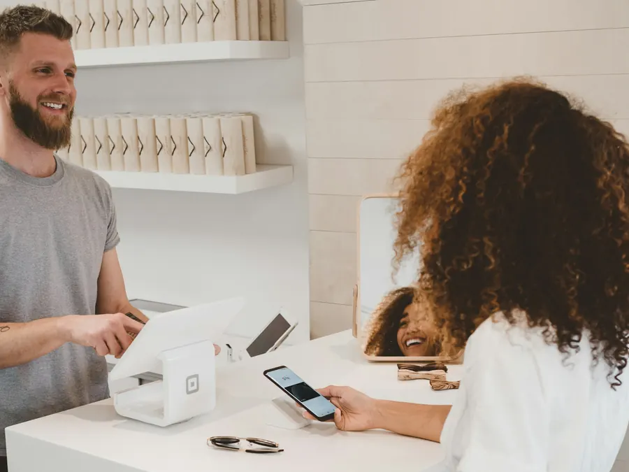 Shop assistant serving a customer paying at the counter